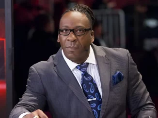 Booker T trägt einen Anzug und blickt ernst in die Kamera