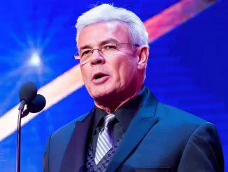 Eric Bischoff steht am Podium und hält eine Rede