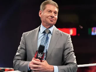 Vince McMahon steht grinsend im WWE Ring