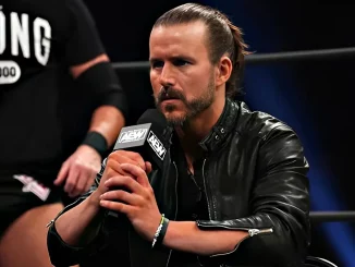 Adam Cole sitzt im Ring und spricht ins AEW Mikrofon