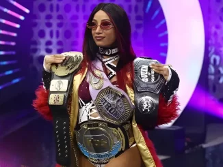 Mercedes Mone präsentiert sich auf der Stage mit ihren Belts