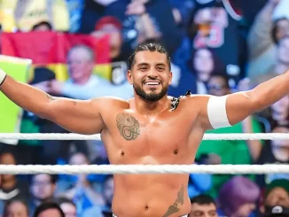 Santos Escobar steht mit ausgestreckten Armen im Ring und lässt sich von Fans bejubeln