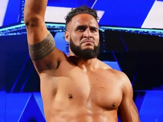 Tama Tonga steht auf der Bühne und streckt den rechten Arm hoch