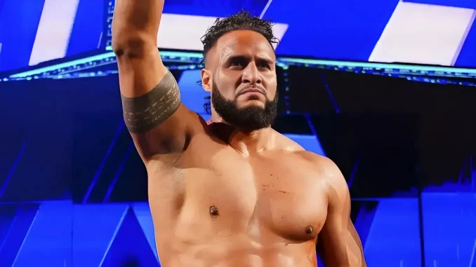 Tama Tonga steht auf der Bühne und streckt den rechten Arm hoch
