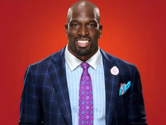 Titus O'Neil trägt einen Anzug und lächelt