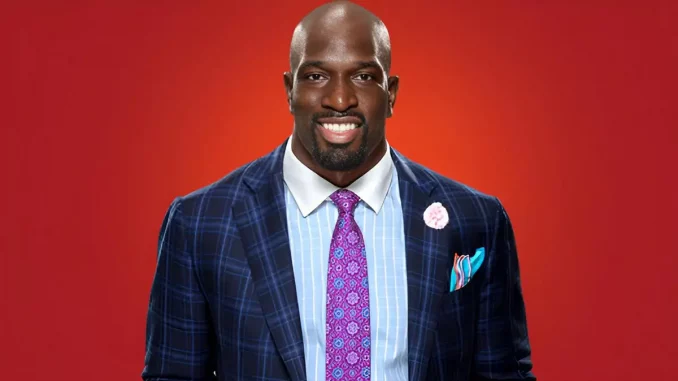 Titus O'Neil trägt einen Anzug und lächelt