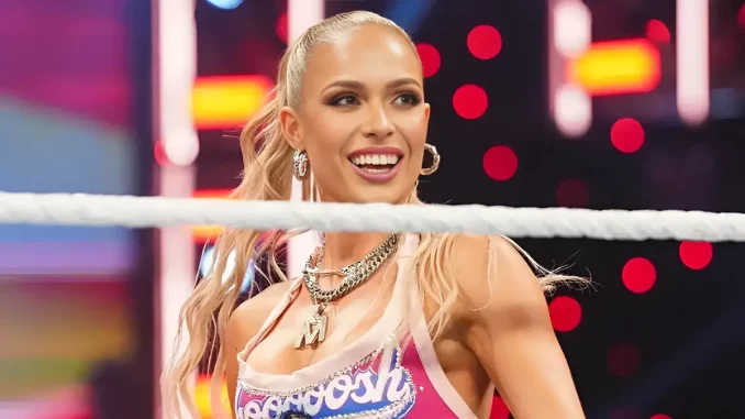 Maxxine Dupri steht lächelnd vor dem Ring