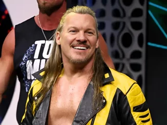 Chris Jericho steht lächelnd im gelb-schwarzen Outfit auf der Bühne