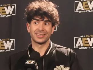Tony Khan sitzt am Podium und lächelt