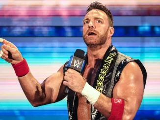 LA Knight steht mit einem WWE Mikrofon auf der Stage und streckt seinen Finger aus