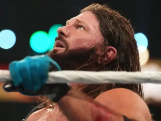 AJ Styles blickt nach oben und hält das Ringseil fest