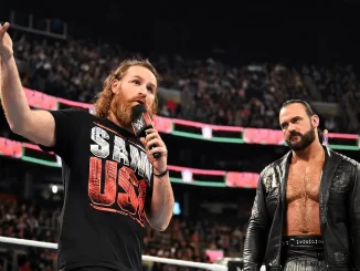 Sami Zayn steht neben Drew McIntyre im Ring und hält ein Mikrofon in der Hand