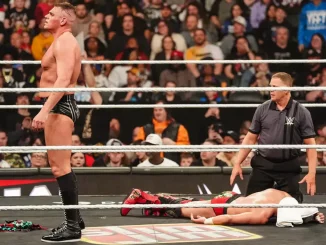 Gunther steht im Ring, während Dragon Lee mit einem weißen Handtuch über dem Kopf auf dem Ringboden liegt