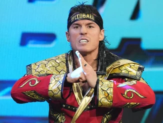 Mike Bailey in rot goldener Ringkleidung vor blau beleuchtetem Hintergrund