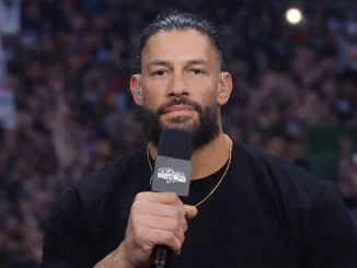 Roman Reigns hält ein Mikrofon in der Hand und blickt direkt in die Kamera