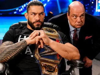 Roman Reigns sitzt mit der Undisputed WWE Championship, während Paul Heyman aufmerksam hinter ihm steht