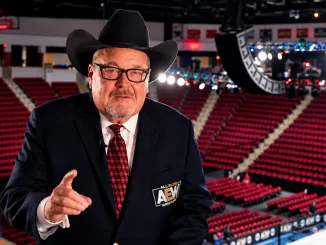 Jim Ross erhebt seinen Finger in einer leeren Arena und blickt dabei in die Kamera