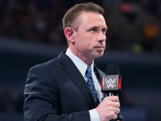 Michael Cole steht nachdenklich am WWE Mikrofon im Ring