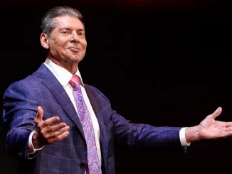 Vince McMahon steht lächelnd auf der Stage und streckt beide Arme aus