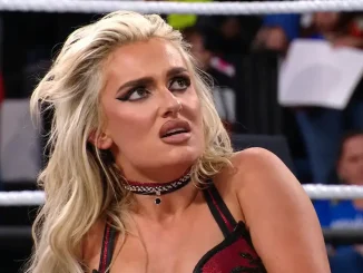 Blake Monroe sitzt mit besorgtem, nach oben gerichtetem Blick im Ring, während die Zuschauermenge im Hintergrund unscharf zu sehen ist