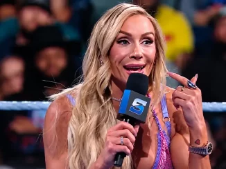 Charlotte Flair steht mit einem Mikrofon im Ring und zeigt während einer Promo auf sich selbst