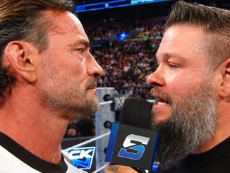 CM Punk steht im Ring und starrt Kevin Owens direkt an, der ein Mikrofon in der Hand hält und spricht