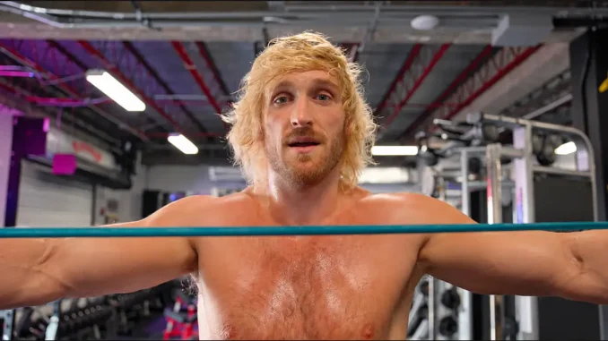 Logan Paul steht mit ausgestreckten Armen in einem Trainingsring hinter einem türkisfarbenen Seil und blickt direkt in die Kamera