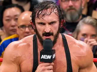 PAC spricht mit einem AEW-Mikrofon im Wrestling-Ring vor dem Publikum