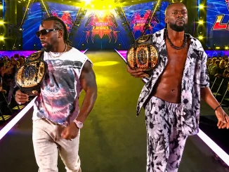 AustinCreed und Kofi laufen mit goldenen Championship-Titeln selbstbewusst über die hell beleuchtete Entrance-Stage, während Fans sie auf beiden Seiten der Arena bejubeln