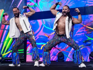 The Young Bucks posieren mit angespannten Armen und lautem Jubel vor einer farbenfrohen LED-Kulisse während ihres energiegeladenen Einzugs