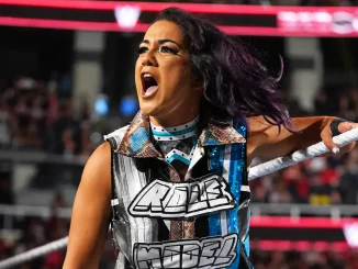 Bayley steht mit erstaunt geöffnetem Mund am Ringseil und reagiert emotional auf das Geschehen im WWE-Ring
