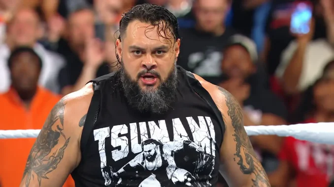 Bronson Reed steht mit intensivem, entschlossenem Blick im WWE-Ring und trägt ein schwarzes „TSUNAMI“-Shirt, während im Hintergrund das Publikum zu sehen ist