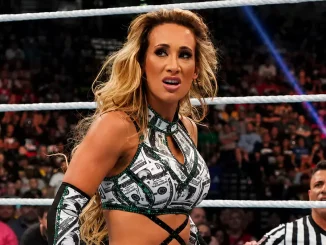 Carmella mit konzentriertem Gesichtsausdruck im Ring, während im Hintergrund ein Ringrichter und die Zuschauer in der Arena zu sehen sind