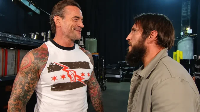 CM Punk ist links mit einem Lächeln zu sehen, während er sich backstage mit dem rechts stehenden Johnny Gargano unterhält