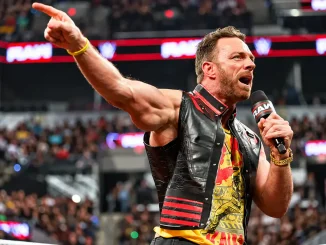 LA Knight steht im Ring, spricht energisch in ein Mikrofon und zeigt mit ausgestrecktem Arm in Richtung Publikum, während die gut gefüllte Arena im Hintergrund zu sehen ist