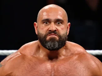 Rusev steht mit ernstem Gesichtsausdruck und weit geöffneten Augen im Wrestlingring, während im Hintergrund ein Ringseil und die abgedunkelte Zuschauerkulisse zu sehen sind