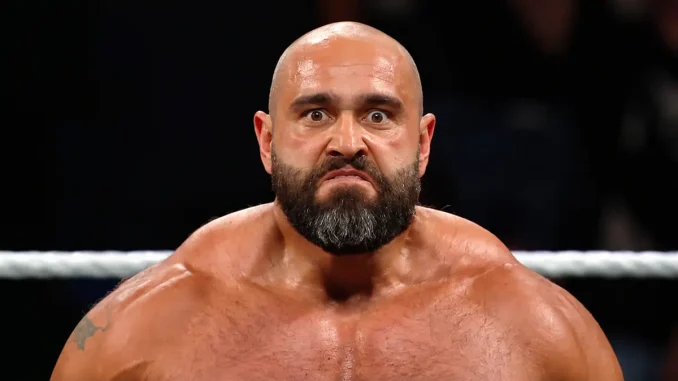 Rusev steht mit ernstem Gesichtsausdruck und weit geöffneten Augen im Wrestlingring, während im Hintergrund ein Ringseil und die abgedunkelte Zuschauerkulisse zu sehen sind