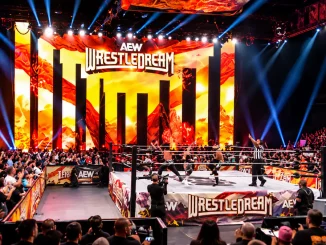 Blick auf den AEW-WrestleDream-Ring vor der orange-gold beleuchteten Bühne mit großem Eventlogo und zahlreichen Zuschauern in der Arena.