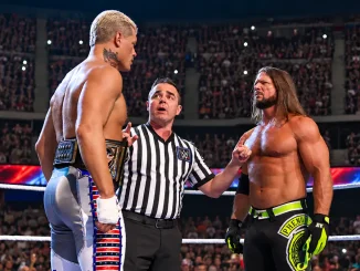 Cody Rhodes und AJ Styles stehen sich im Wrestlingring angespannt gegenüber, während der Ringrichter zwischen beiden vermittelt und die voll besetzte Arena im Hintergrund zu sehen ist.