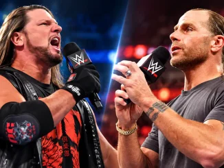 AJ Styles (links) und Shawn Michaels (rechts) halten jeweils ein WWE-Mikrofon in der Hand. Beide sind vor einem farbig beleuchteten Arenahintergrund zu sehen.