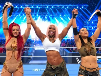B-Fab, Jade Cargill und Michin stehen gemeinsam im WWE-Ring bei SmackDown, halten ihre Arme hoch und präsentieren ihre Championship-Belts.