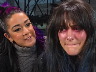 Bayley links mit lila Haarsträhnen neben Lyra Valkyria mit dunklen Haaren und gerötetem Augenbereich im Backstage-Bereich.