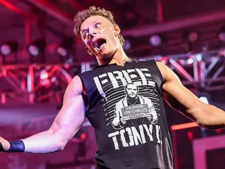 Channing „Stacks“ Lorenzo mit ausgestreckten Armen und offenem Mund trägt ein schwarzes „FREE TONY!“-Shirt vor einer rot beleuchteten Kulisse.