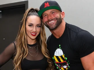 Das Bild zeigt Chelsea Green und Matt Cardona, die nah nebeneinander lächelnd in einem Backstage- oder Flurbereich für die Kamera posieren.