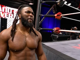 Keanu Carver steht mit ernstem Gesichtsausdruck neben dem Wrestling-Ring. Im Hintergrund sind die Ringseile und eine LED-Wand mit seinem Namen zu sehen.