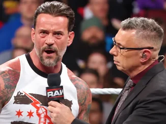 CM Punk spricht mit ernster Miene in ein WWE Raw-Mikrofon, das Michael Cole während eines Interviews im Wrestling-Ring hält. Im Hintergrund sind zahlreiche Zuschauer in der Arena zu sehen.