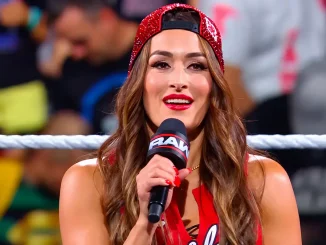 Nikki Bella mit roter Kappe und Mikrofon im Wrestling-Ring.