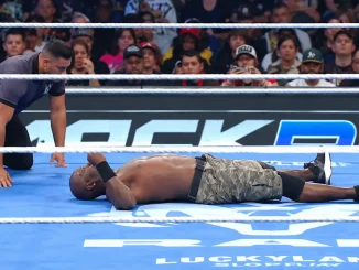 R-Truth liegt auf dem Rücken im Ring, während der Ringrichter neben ihm kniet. Im Hintergrund sind Zuschauer zu sehen.