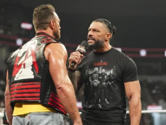 Roman Reigns steht LA Knight direkt im Ring gegenüber und teilt ihm etwas über ein Mikrofon mit.