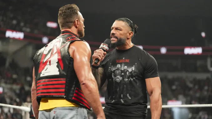 Roman Reigns steht LA Knight direkt im Ring gegenüber und teilt ihm etwas über ein Mikrofon mit.